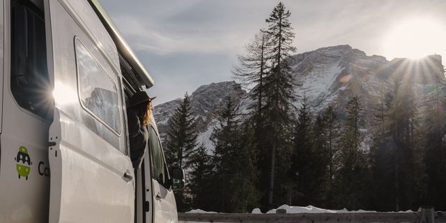 A person leans out of a CamperBoys van watching the view of the mountains.