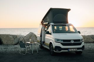 Woman looking out of the camper at the sea at sunset in Slovenia