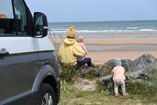 Mutter mit zwei Kindern mit Camper am Strand in Holland