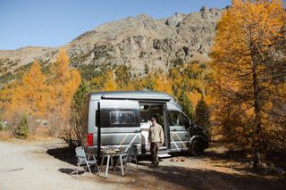 Ein Mann steht beim Camper in den Bergen in Italien