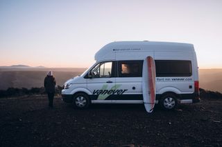 A woman is watching the sunset by the camper